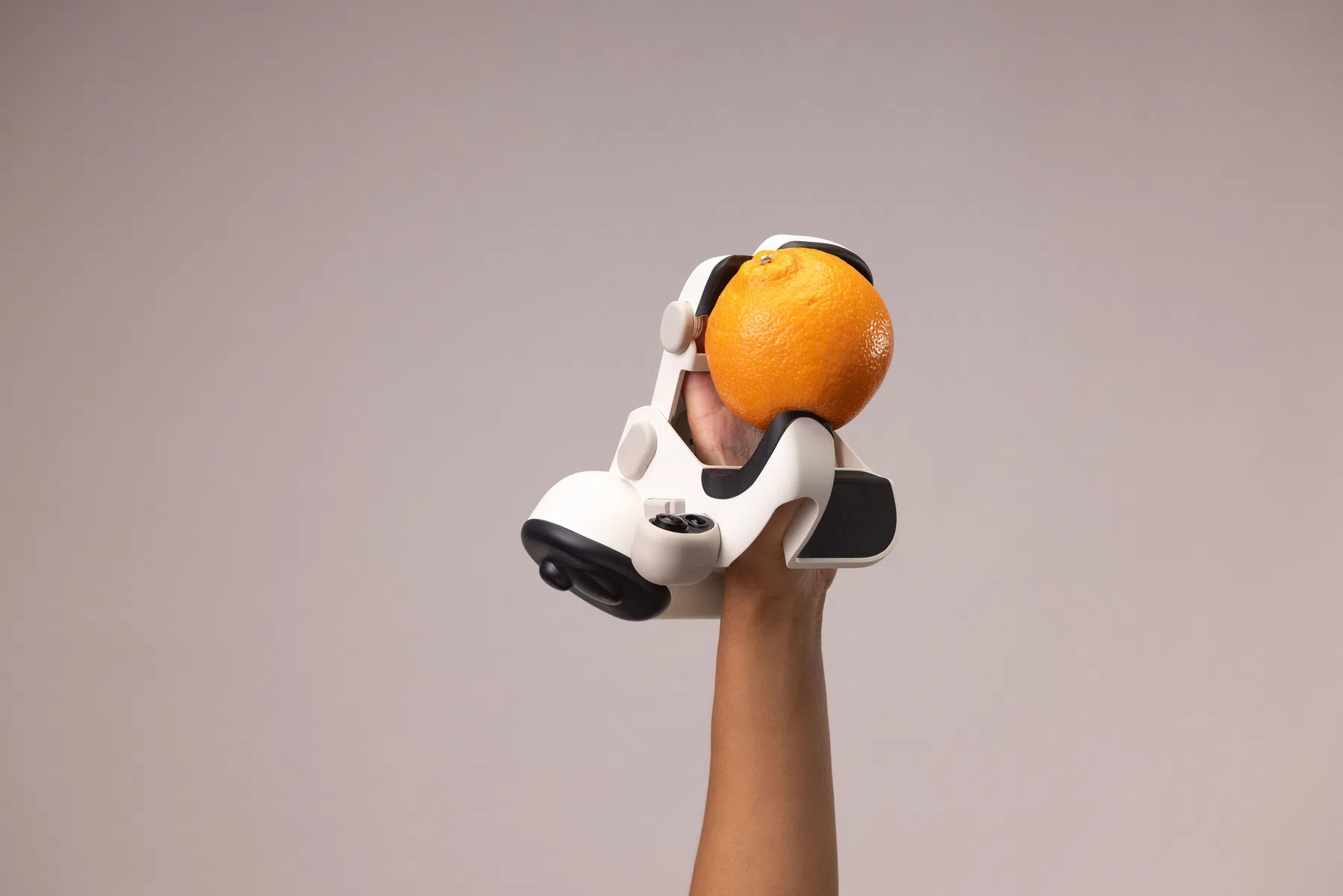 Een robotische handschoen die een sinaasappel vastheeft.